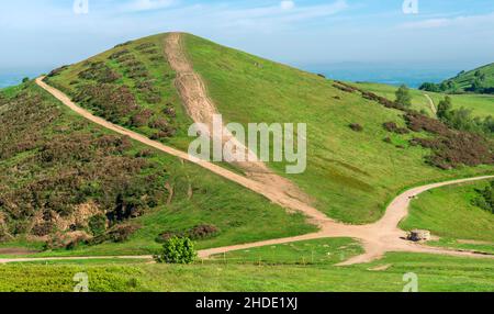 Sugarloaf Hill coperto da lussureggiante erba verde e bagnata dalla luce del sole estiva. Il sentiero del camminatore si divide in diverse direzioni alla base della collina Foto Stock