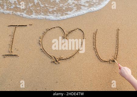 Messaggio ti amo sulla sabbia con la donna del disegno a mano sulla spiaggia Foto Stock