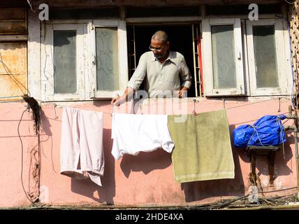 Un uomo appeso lavanderia lavata su una corda fuori dalla sua finestra di casa a Mumbai, India. Foto Stock