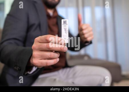 Mani di persona irriconoscibile felice dopo il risultato negativo della prova a casa. Uomo che fa il test rapido dell'antigene, sars-cov-2, coronavirus, covid-1 Foto Stock