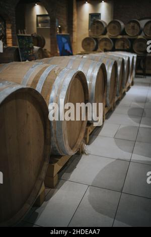 Shot verticale di botti di vino in legno in una cantina di stoccaggio Foto Stock