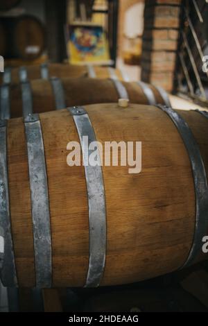 Shot verticale di botti di vino in legno in una cantina di stoccaggio Foto Stock