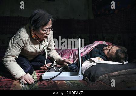 Pechino, la provincia cinese di Shaanxi. 18th Jan 2021. LU Shengmei (L) effettua un trattamento medico gratuito al villager Qiao Aifen, che è confinato a letto a causa della paralisi all'interno della sua dimora grotta, nel villaggio di Hejiagou della contea di Jiaxian, città di Yulin, provincia di Shaanxi della Cina nord-occidentale, 18 gennaio 2021. Nell'anno del 1968, Lu si è laureato in un collegio medico a Pechino e ha scelto di lavorare nella remota Jiaxian. Aveva lavorato nella contea fino al suo ritiro nel 1999. Da allora, ha continuato ad offrire il trattamento libero alla gente locale. Credit: Tao Ming/Xinhua/Alamy Live News Foto Stock