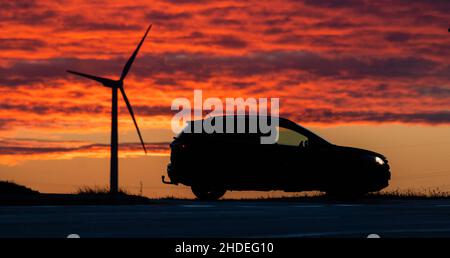 06 gennaio 2022, bassa Sassonia, Groß Förste: Un'auto guida lungo la strada a B6 tronco nel distretto di Hildesheim mentre il sole che sorge gira il cielo del mattino rosso profondo. Foto: Julian Stratenschulte/dpa Foto Stock