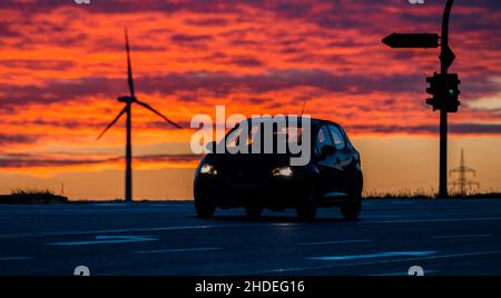 06 gennaio 2022, bassa Sassonia, Groß Förste: Un'auto guida lungo la strada a B6 tronco nel distretto di Hildesheim mentre il sole che sorge gira il cielo del mattino rosso profondo. Foto: Julian Stratenschulte/dpa Foto Stock