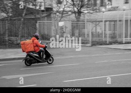 Consegna di cibo ragazzo su scooter con contenitore isotermico cibo Foto Stock