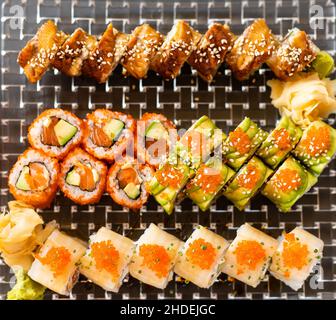 Cucina giapponese a soffitto con sushi. Maki Sands Rolls con tonno, salmone, gamberi, granchio e avocado. Vista dall'alto di sushi assortiti, menu a volontà. Arcobaleno Foto Stock