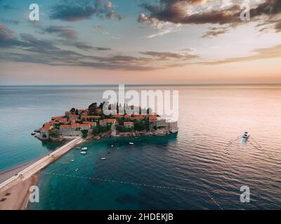 Sveti Stefan Island alla luce dei raggi rosa del tramonto del sole. Montenegro Foto Stock