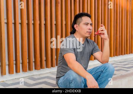 Uomo indigeno che usa il telefono mobile all'aperto Foto Stock
