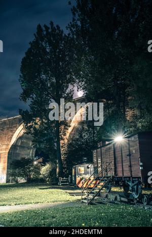 Colpo verticale di vagoni vecchi del treno contro il viadotto di Nagold in Germania di notte Foto Stock