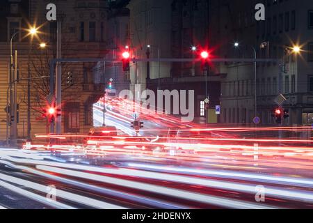 Segnale rosso al semaforo e leggero sentiero delle auto durante gli ingorghi. Strada urbana trafficata di notte. Praga, Repubblica Ceca Foto Stock