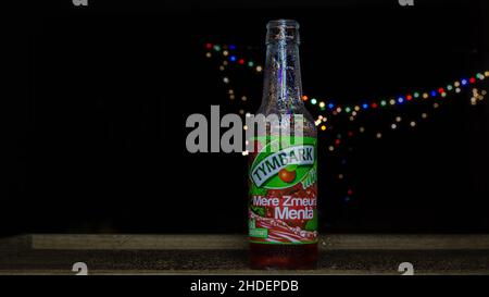 Primo piano di un bicchiere freddo di Tymbrik con succo di mela isolato su sfondo nero con luci colorate Foto Stock