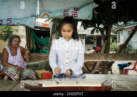 Una bella ragazza thailandese che suona Khim, il tradizionale strumento musicale thailandese vicino alla nonna all'aperto su pannello di legno. Concetto di tempo libero e hobby. Foto Stock