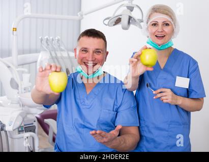 Stomatologi sorridenti che mostrano mele Foto Stock