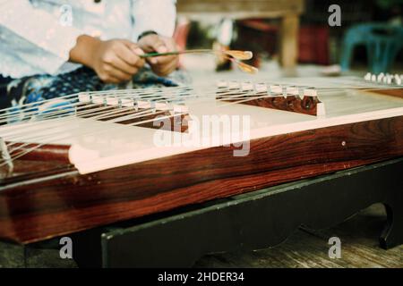 Ragazza thailandese che suona Khim, il tradizionale strumento musicale thailandese. Concetto di tempo libero e hobby. Meditazione ascoltando musica. Foto Stock