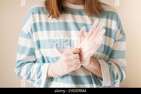 Donna stringendo guanti in vinile trasparente sulle mani Foto Stock