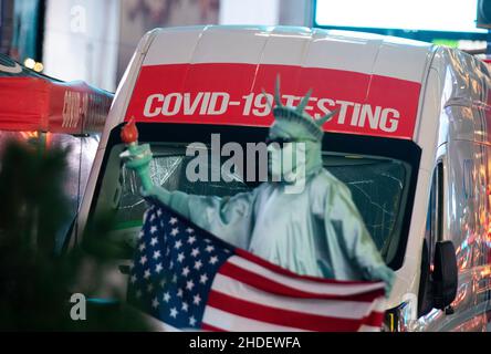 (220106) -- WASHINGTON, 6 gennaio 2022 (Xinhua) -- Un artista di strada attende i clienti vicino ad un COVID-19 mobile che prova il luogo su Times Square a New York, gli Stati Uniti, 20 dicembre 2021. (Xinhua/Wang Ying) Foto Stock