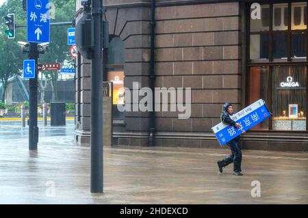 (220106) -- PECHINO, 6 gennaio 2022 (Xinhua) -- Un membro del personale porta una guida di bordo abbattuta da gales nella Shanghai della Cina orientale, 25 luglio 2021. (Xinhua/Wang Xiang) Foto Stock