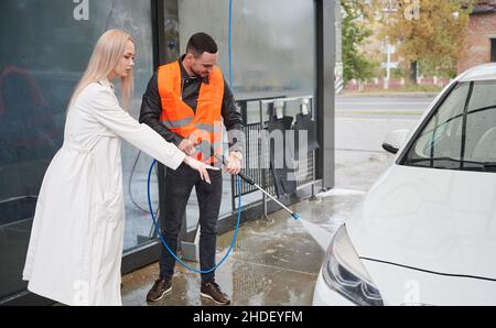 Donna auto lavaggio con idropulitrice a pressione Foto stock - Alamy