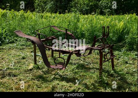 Vecchio macchinario agricolo. Aratro arrugginito vecchio sul bordo di un campo agricolo Foto Stock