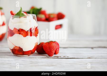 Sana prima colazione di parfaits fragole a base di frutta fresca, e yogurt su un rustico tavolo bianco. Messa a fuoco selettiva con sfondo sfocato. Foto Stock