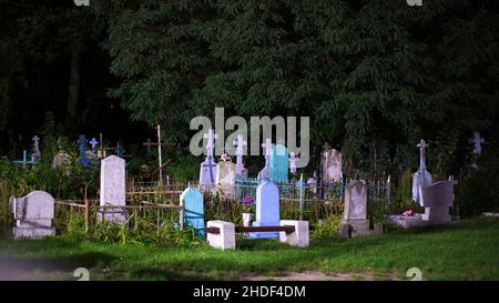Vista sul vecchio cimitero della città ortodossa in estate di notte. Vecchie lapidi multicolore e croci. Foto Stock
