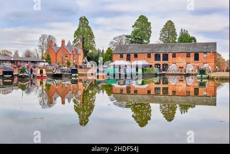 Barche strette ormeggiate accanto a magazzini convertiti al bacino di Union Wharf del canale Grand Union, Market Harborough, Inghilterra. Foto Stock