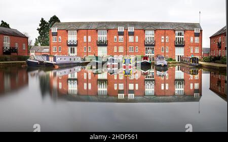 Barche strette ormeggiate accanto a magazzini convertiti al bacino di Union Wharf del canale Grand Union, Market Harborough, Inghilterra. Foto Stock