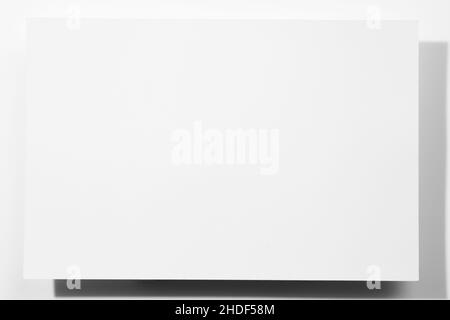 Grande foglio di carta bianco di cartone di colore bianco - striscione a forma di rettangolo con ombre che cadono su sfondo bianco. Carta mock up. Spazio di copia Foto Stock