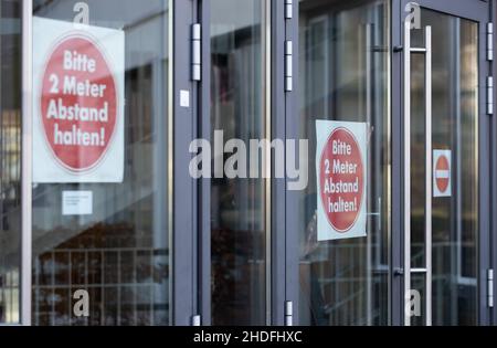 Bielefeld, Germania. 06th Jan 2022. Un janitor tiene un cartello "si prega di mantenere 2 metri di distanza" dalla finestra in una classe dalla Max Planck High School per il fotografo. Le attività scolastiche si trovano ad affrontare sfide importanti durante la crisi di Corona. Le misure comportamentali, le misure igieniche e protettive, la ventilazione, l'uso della protezione bocca-naso e i casi di quarantena devono essere gestiti ripetutamente. Credit: Friso Gentsch/dpa/Alamy Live News Foto Stock