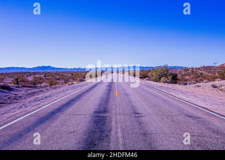 Strada senza fine attraverso il deserto fotografata vicino a Primm sul confine tra il Nevada, la California e l'Arizona Foto Stock