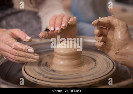 Ceramisti femminili non riconoscibili che lavorano su ruota vasai, gettando pentola Foto Stock