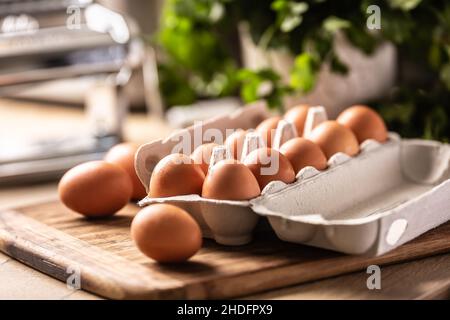 Una scatola di cartone piena di uova di pollo fresche sul banco della cucina. Foto Stock