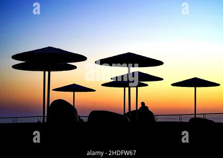 Silhouette di ombrelloni sulla spiaggia al tramonto. Fotografato a marzo sulla spiaggia di Tel Aviv, Israele Foto Stock