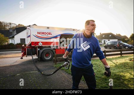 Itzehoe, Germania. 09th Nov 2021. Un dipendente di un'azienda produttrice di gasolio e olio di riscaldamento tira un tubo flessibile con ugello per la consegna dell'olio di riscaldamento a un cliente in un edificio di appartamenti. Credit: Christian Charisius/dpa/Alamy Live News Foto Stock