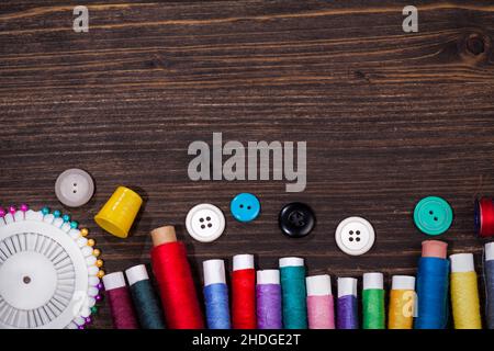Forbici, rocchetti con filo e aghi sul vecchio sfondo di legno. Sfondo vintage Foto Stock