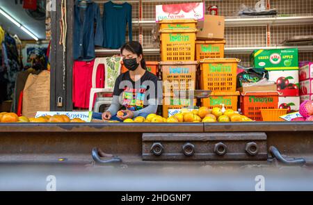 Bangkok, Tailandia. 5th Jan 2022. Un fornitore è visto al mercato ferroviario di Maeklong nella provincia di Samut Songkhram, Tailandia, 5 gennaio 2022. Nel Maeklong Railway Market, costruito lungo una linea ferroviaria, si raggiunge un compromesso tra venditori ambulanti e treni pendolari. Quando la pista ferroviaria è libera, i proprietari di stalle possono allestire stalle a volontà. Prima della pandemia COVID-19, il mercato aveva attirato molti turisti. Oggi, a causa della diminuzione dei passeggeri, il numero di treni che effettuano la navetta ogni giorno è stato ridotto da otto a due. Credit: Wang Teng/Xinhua/Alamy Live News Foto Stock