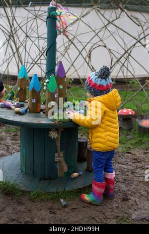 Un bambino di 3 anni che gioca all'aperto in una scuola forestale, Regno Unito Foto Stock