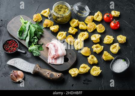 Tortellini crudi fatti in casa con prosciutto stagionato, su sfondo nero Foto Stock