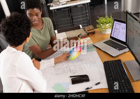 Architetti femminili multirazziali che discutono sopra il campione di colore alla scrivania in ufficio creativo Foto Stock