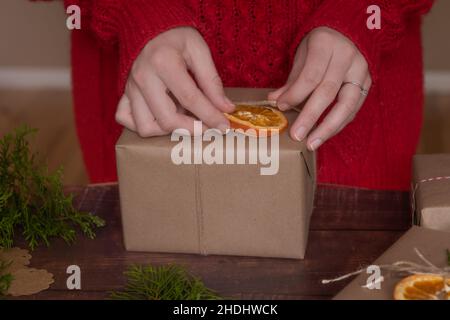 Le mani della donna che decorano i regali di Natale e di Capodanno durante le vacanze in inverno Foto Stock