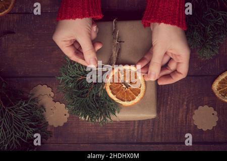 Le mani della donna che decorano i regali di Natale e di Capodanno durante le vacanze in inverno Foto Stock