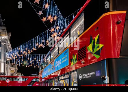Luci di Natale di notte (2021) a Oxford Circus (al centro di Oxford Street) con autobus a due piani rossi - West End, Londra, Inghilterra, Regno Unito Foto Stock