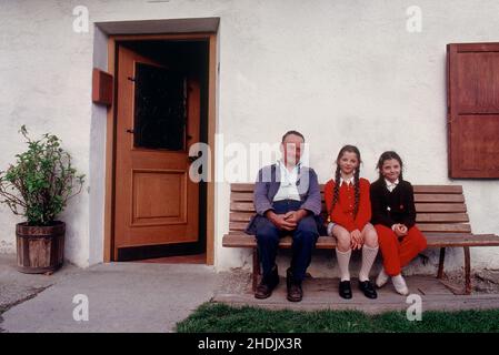 Nonno con nipoti seduti su una panchina di fronte alla casa colonica in Austria . Foto Stock