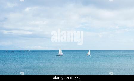 Due barche a vela navigano nelle acque calme di Fuengirola in una giornata invernale nuvolosa. Foto Stock