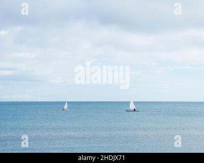 Due barche a vela navigano nelle acque calme di Fuengirola in una giornata invernale nuvolosa. Foto Stock