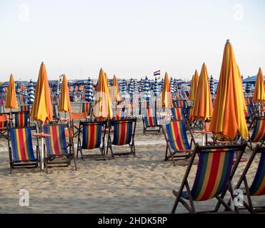 Ombrelloni e sdraio a righe arancioni vuoti e in attesa sulle spiagge nei pressi di Pisa, Italia Foto Stock