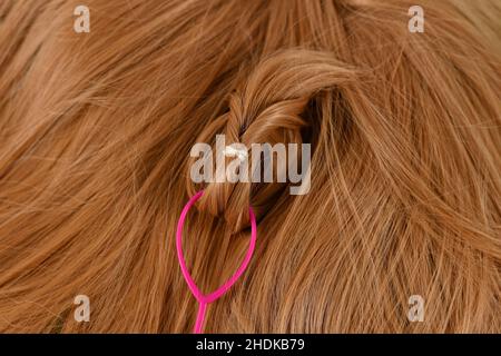 Primo piano dello strumento per lo styling dell'ago per capelli a coda di cavallo utilizzato sui capelli biondi Foto Stock