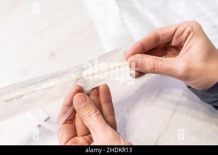 Estrarre il tampone dal test. Una giovane donna che fa il test rapido dell'antigene a casa sua, sars-cov-2 test. Misure di sicurezza nel pannago del coronavirus Foto Stock