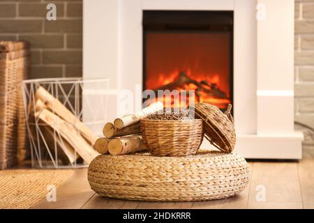 Cestino di vimini con pellet e legna da ardere su pouf in soggiorno Foto Stock